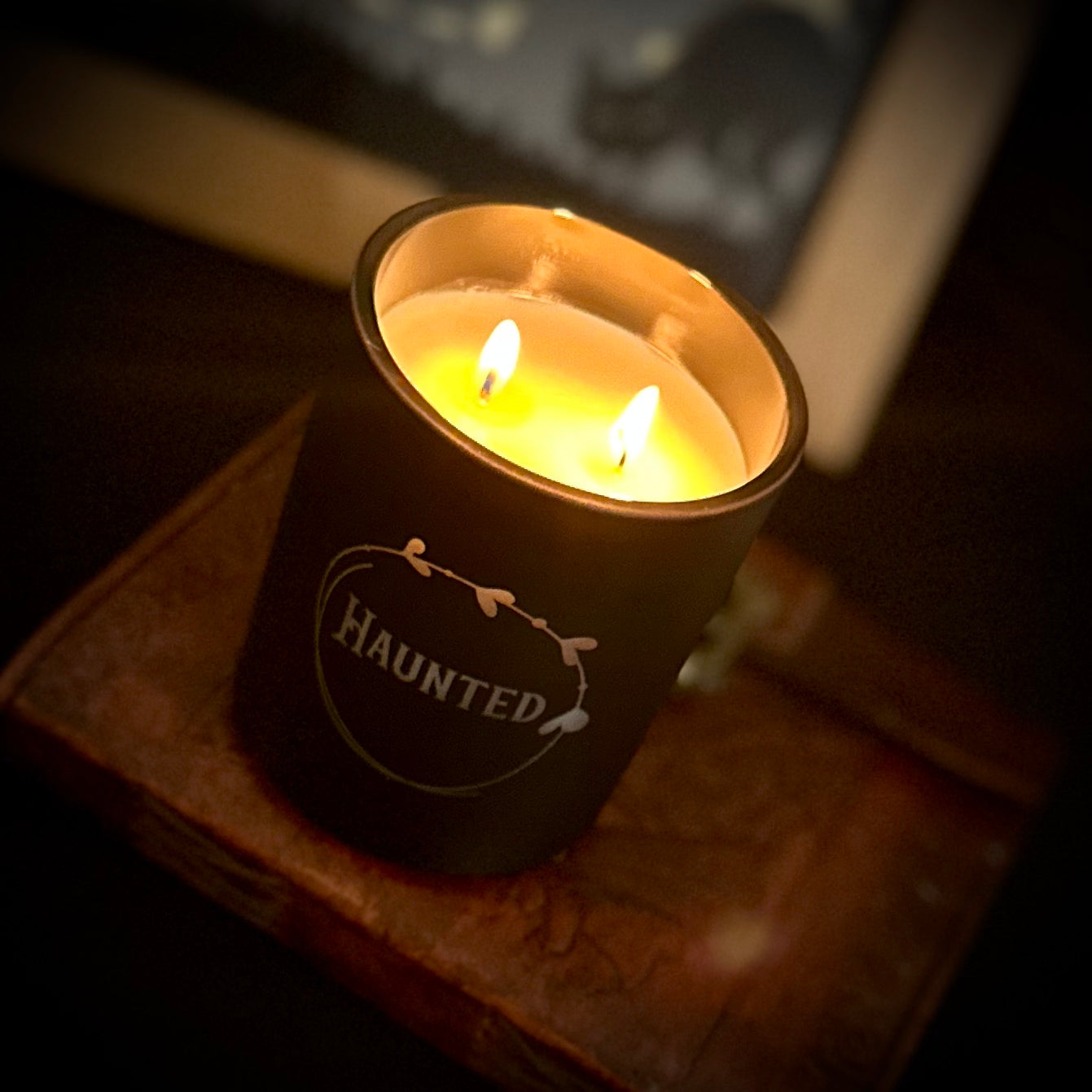 Flickering flame inside a black haunted candle jar, casting smoky honey-tobacco scent and haunting shadows.