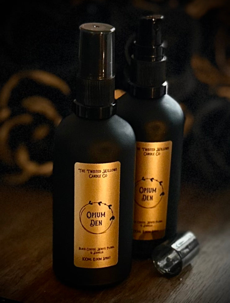 Two black spray bottles labeled 'Opium Den' on a dark background
