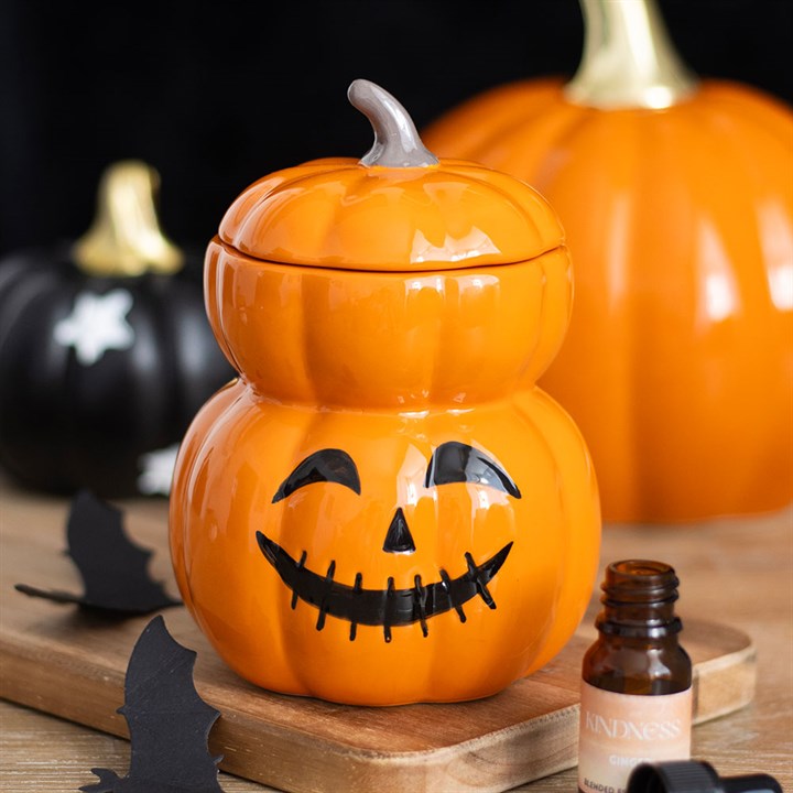 Close up of stacked pumpkin wax melter surrounded by halloween pumpkins.