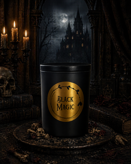 Matte black glass jar with black wooden lid and gold label reading "Black Magic." Resting on an antique mirror beside a tarot card and fresh black cherries.