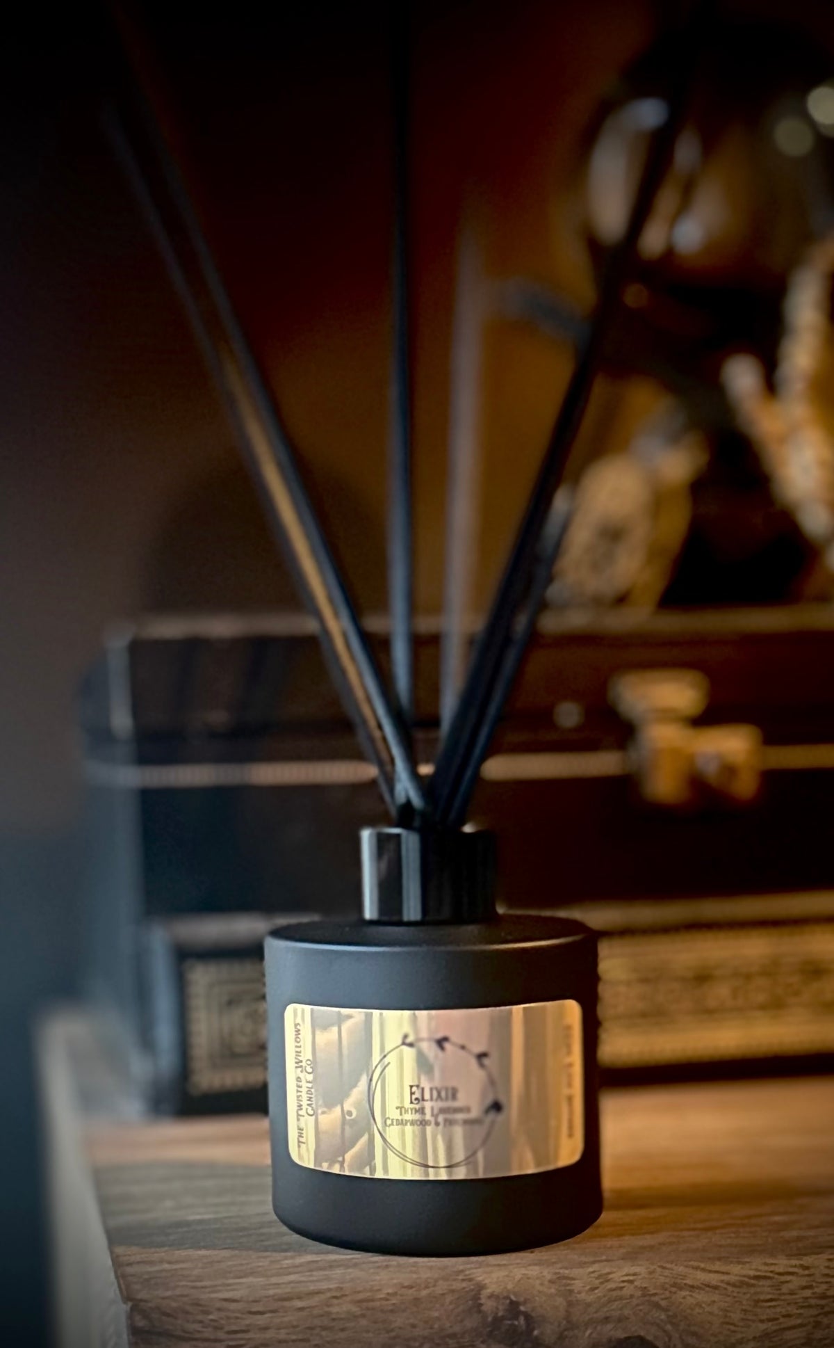 Elixir reed diffuser in matt black glass with metallic gold label, scented with thyme, lavender, patchouli and cedarwood