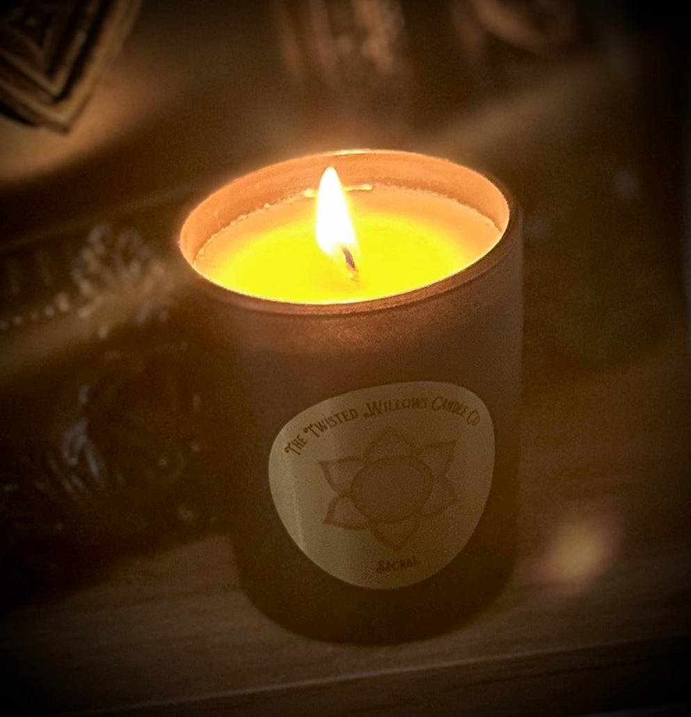 Sacral chakra candle glowing on a dimly lit altar.