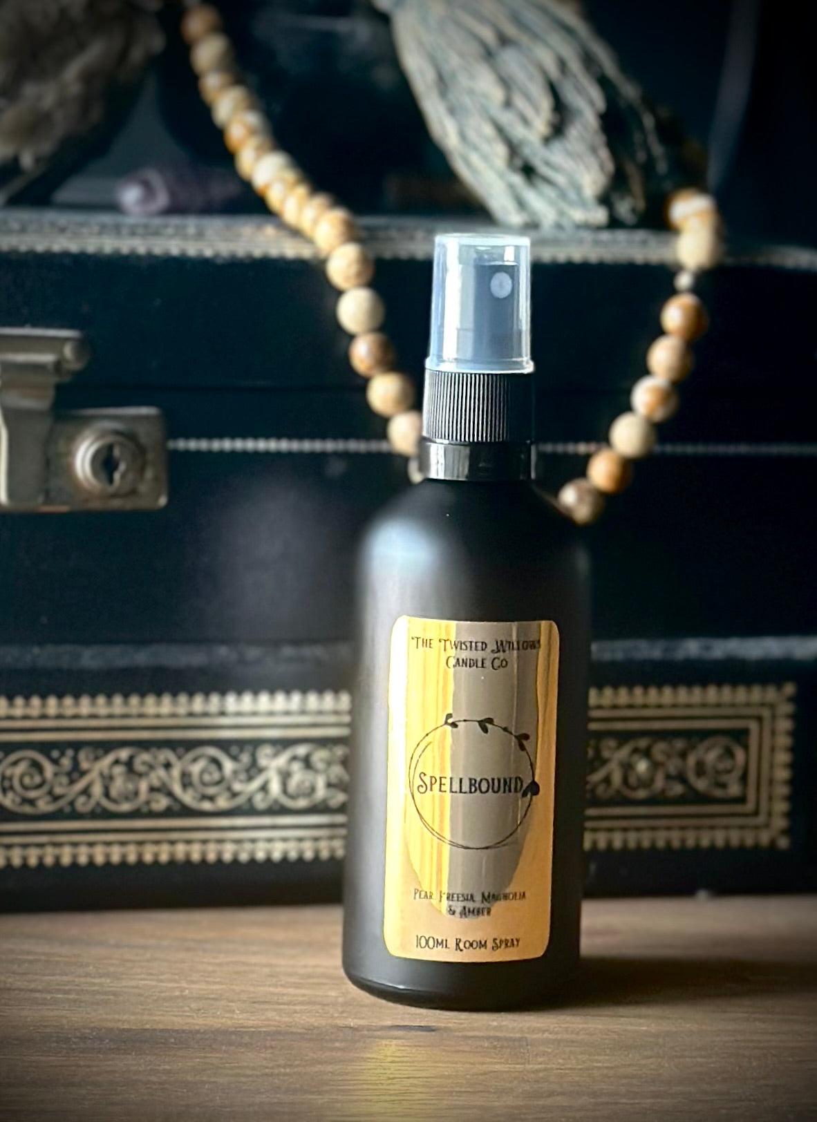 Spellbound Room Spray in a matte black glass bottle and gold label scented with pear and freesia