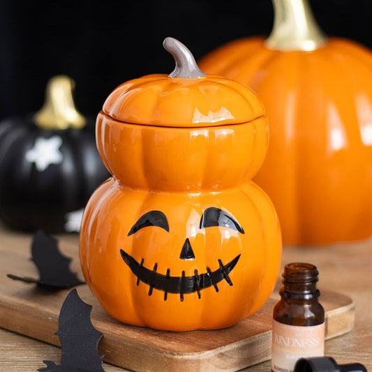 Close up of stacked pumpkin wax melter surrounded by halloween pumpkins.