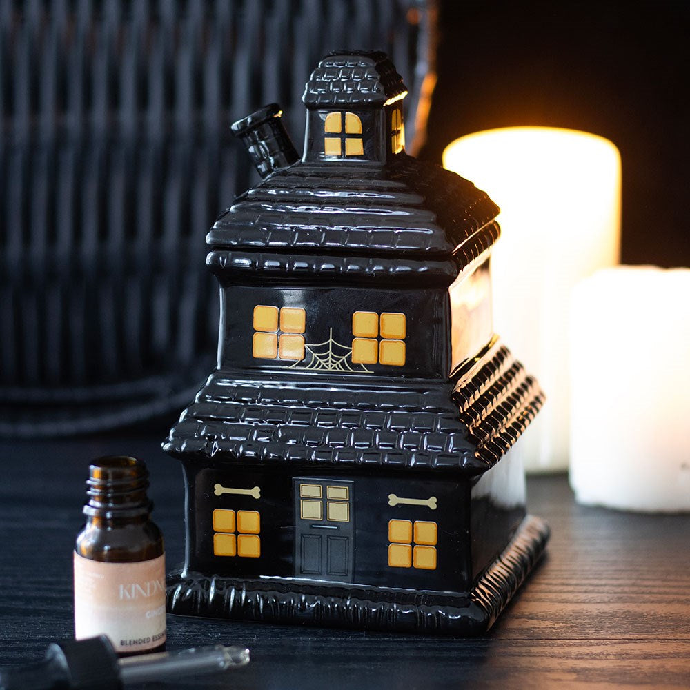 Black ceramic haunted house wax melter and oil burner with glowing orange windows.