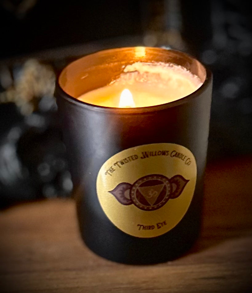 Third Eye Chakra soy candle flickering on altar with tarot cards, surrounded by dried herbs and obsidian stones.