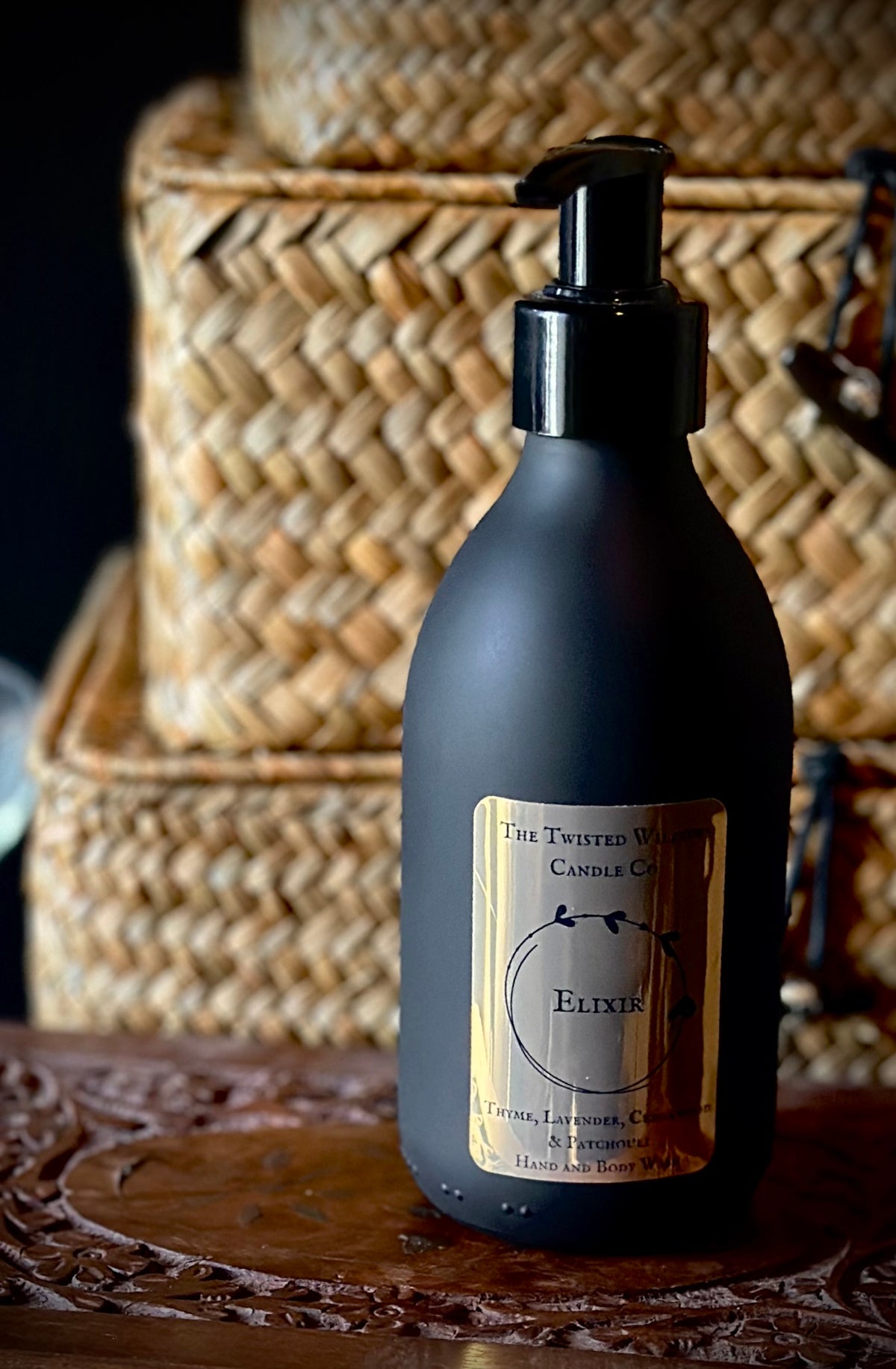 Elixir hand and body wash in matt black glass jar with metallic gold label and thyme, lavender, patchouli and cedarwood fragrance